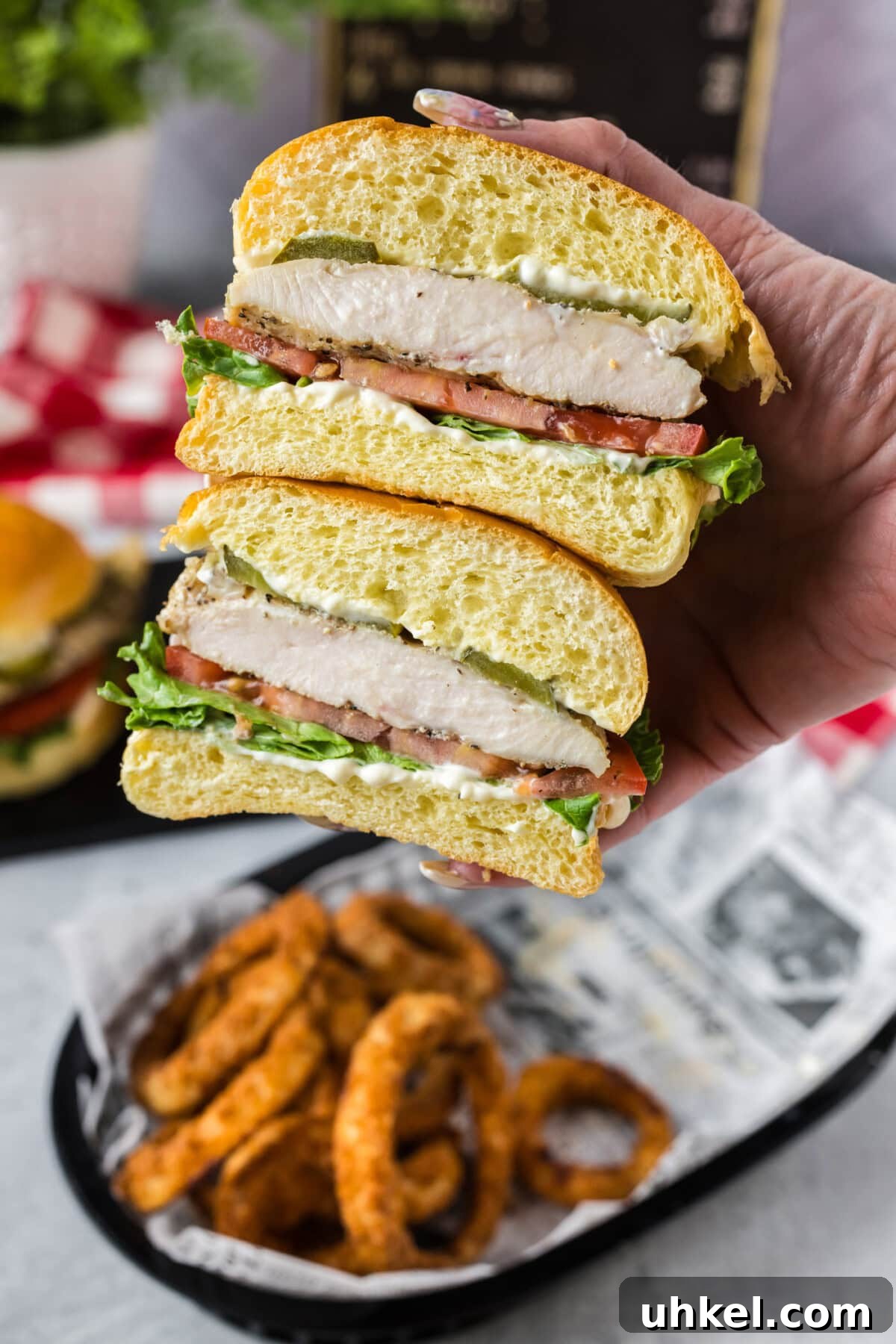 Crispy Chicken Sandwich Recipe with Tangy Slaw and Pickles 8 Hand holding a Chicken Sandwich that has been cut in half