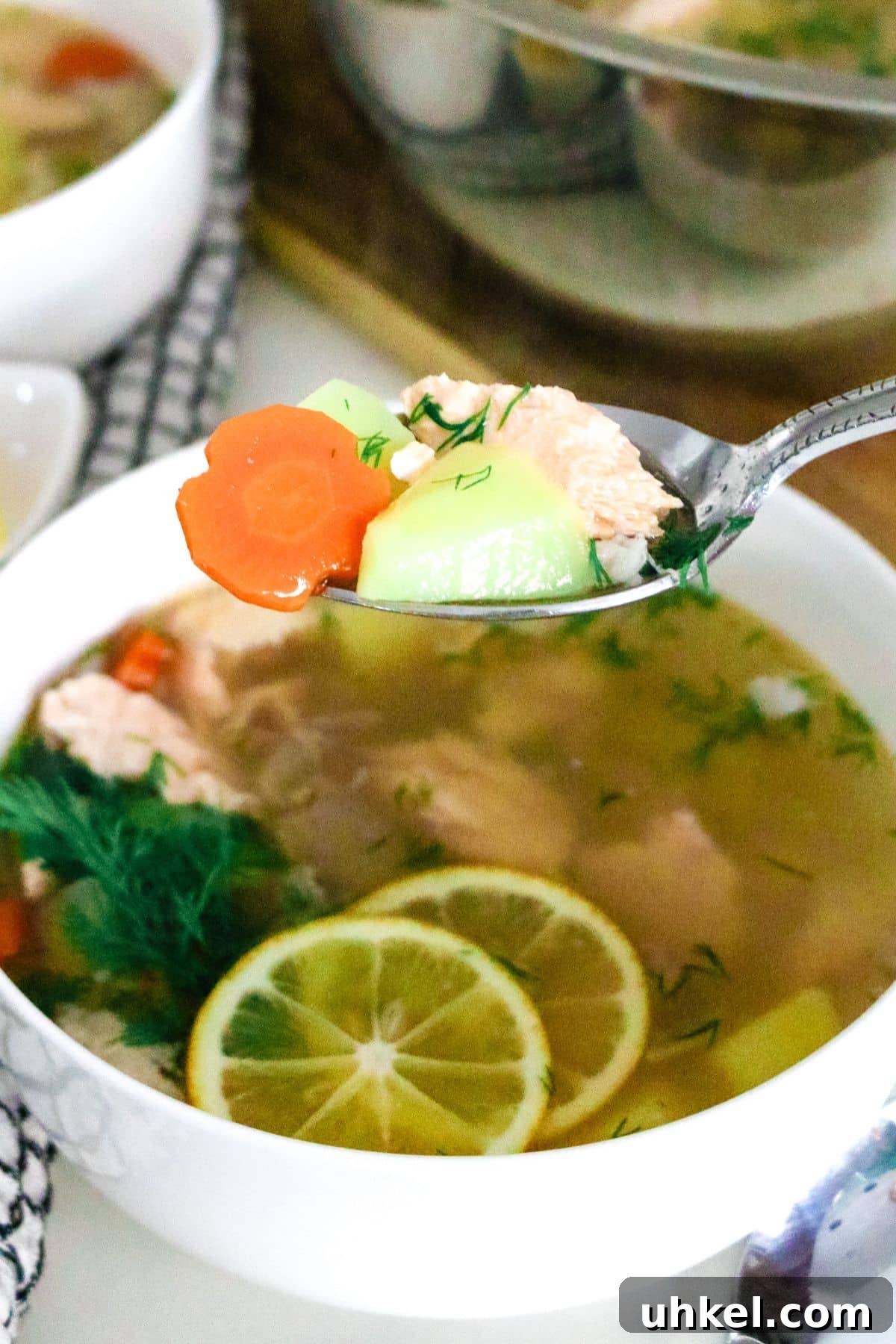 Authentic Ukha Fish Soup Recipe: Clear Russian Fisherman’s Broth 5 spoon full of fish soup over a bowl of fish soup on a white counter