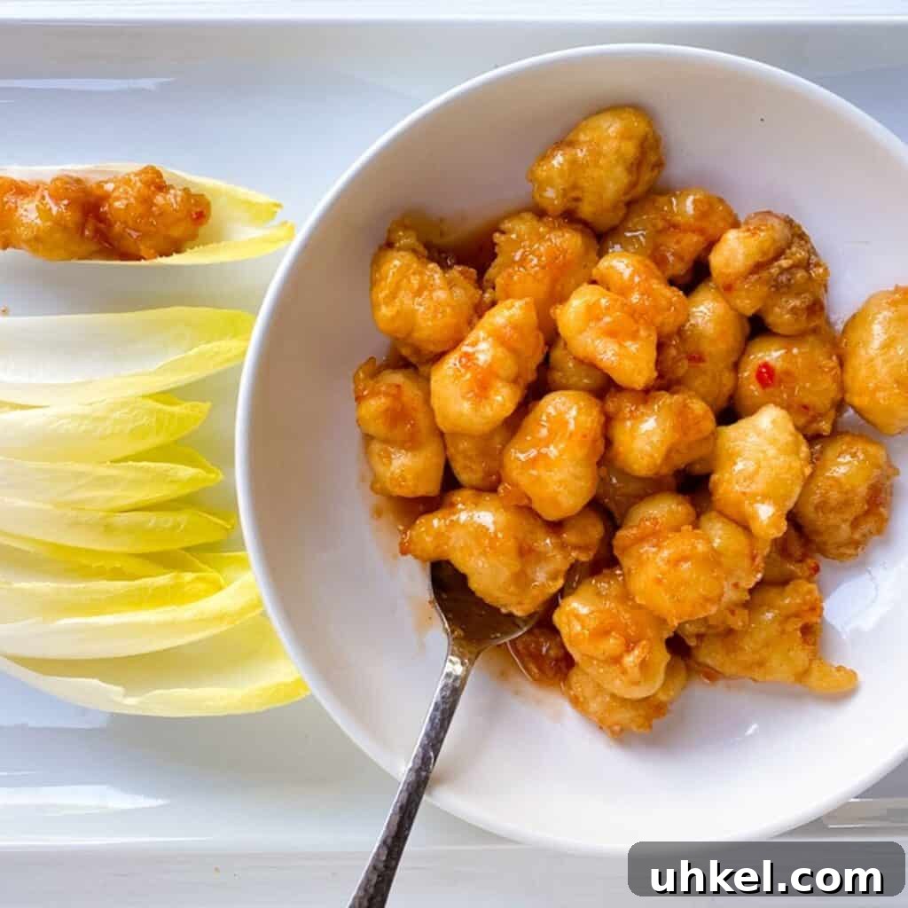 97 Crowd-Pleasing Appetizer Ideas for Parties and Gatherings 4 shrimp tempura with chili sauce in a white bowl with a spoon and endive leaves on the side