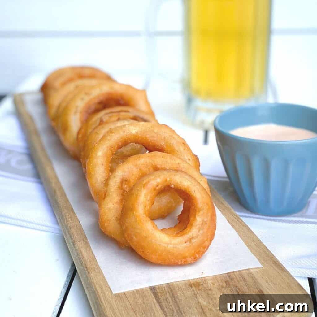 97 Crowd-Pleasing Appetizer Ideas for Parties and Gatherings 10 crispy beer battered onion rings appetizer on a wooden plank with dipping sauce and a beer on the side