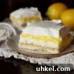 A slice of lemon pudding lush on a plate with whipped cream topping.