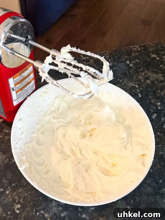 Decadent Lemon Lush Dessert with Graham Cracker Crust 2 A bowl of cream cheese and sugar mixed together using an electric hand mixer.