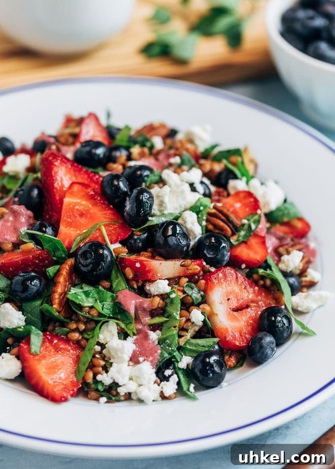 Wheat Berry Salad with Mixed Berry Vinaigrette wheat berry salad on a white plate with berries and goat cheese {sponsored}