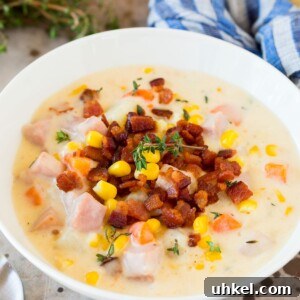 A bowl of ham and corn chowder garnished with bacon.