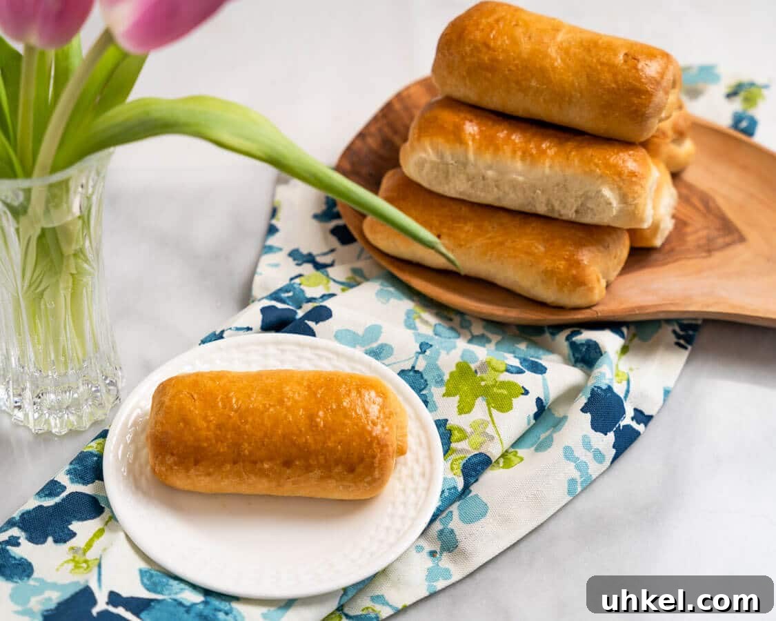 Ground Lamb Stuffed Buns Recipe – Savory Meat-Filled Bread 3 Angled photo of a meat bun on a plate with a stack of meat-filled buns in the background.