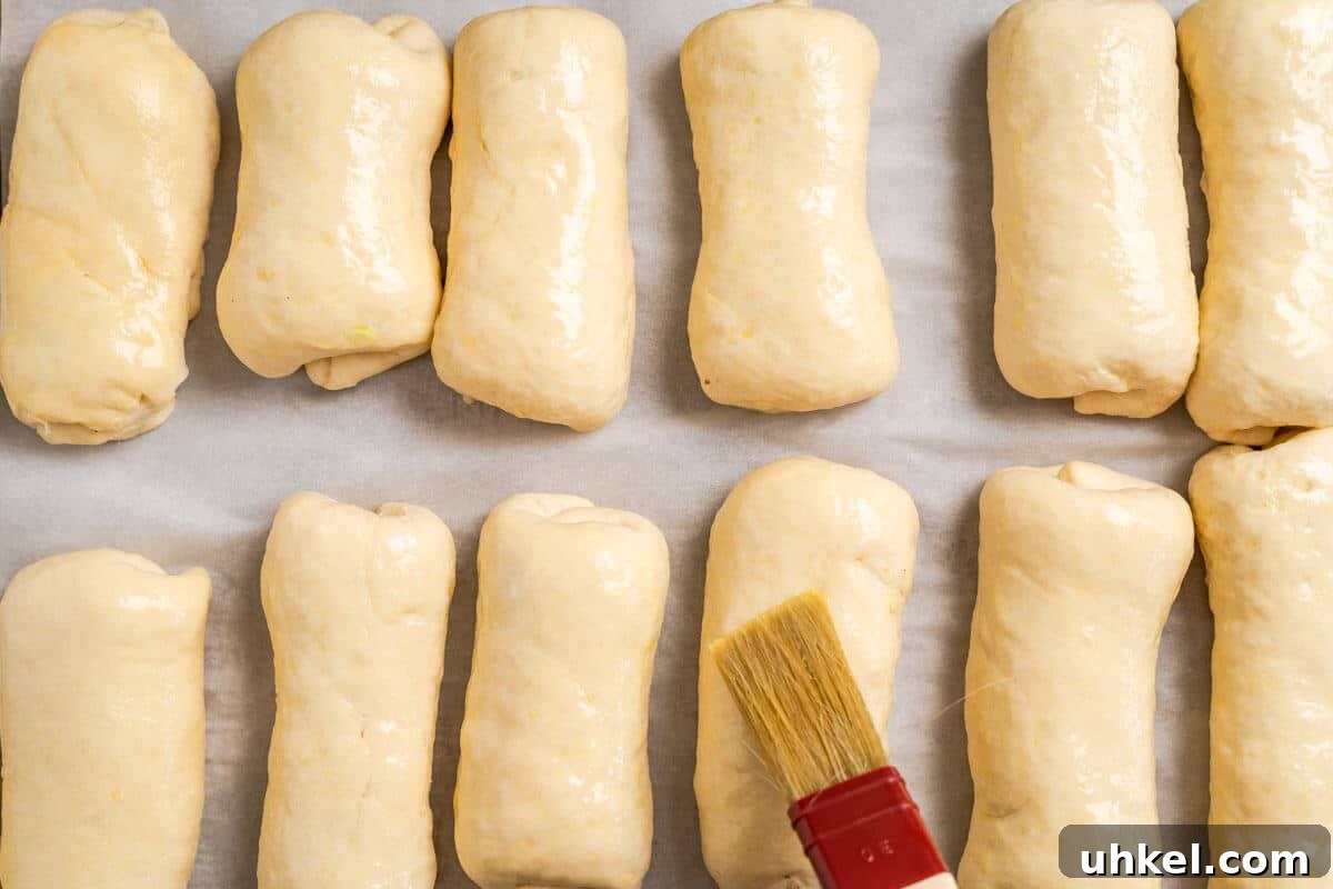 Ground Lamb Stuffed Buns Recipe – Savory Meat-Filled Bread 8 Egg wash being applied to risen shaped and filled dough.