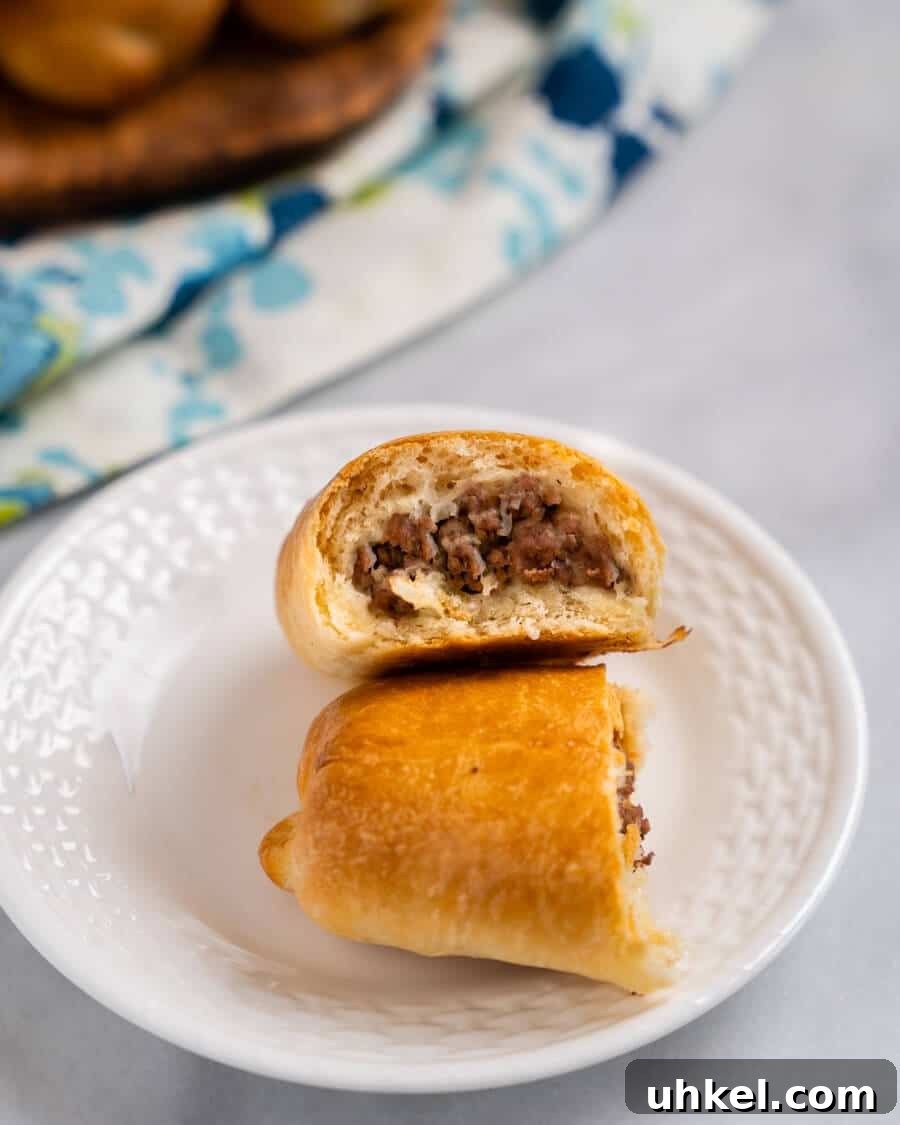 Ground Lamb Stuffed Buns Recipe – Savory Meat-Filled Bread 9 A bread roll cut in half showing cooked meat filling.