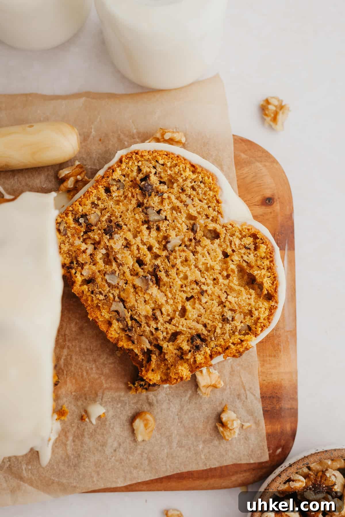 Maple-Glazed Pumpkin Walnut Bread Recipe 2 A slice of pumpkin bread on a wooden cutting board.