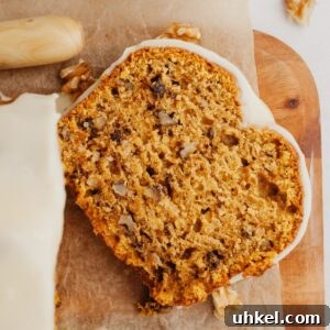 Maple-Glazed Pumpkin Walnut Bread Recipe 14 A slice of pumpkin bread on a wooden cutting board.
