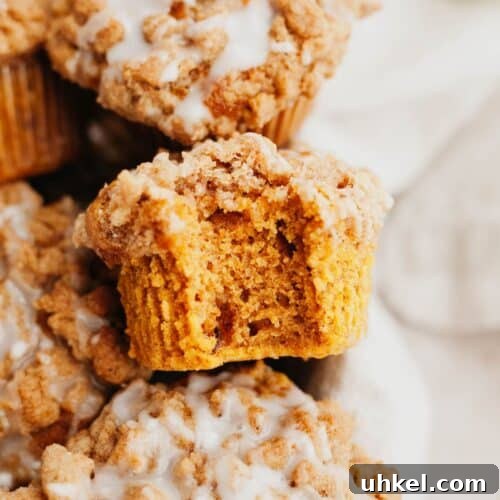 A close up of a pumpkin muffin with a streusel topping, a bite has been taken out of it.