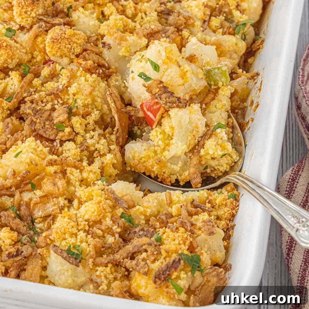 15 Perfect Side Dishes to Serve with Ham This Holiday 13 Golden baked cauliflower casserole with bell peppers and cornbread topping, served in a white dish with a vintage spoon.