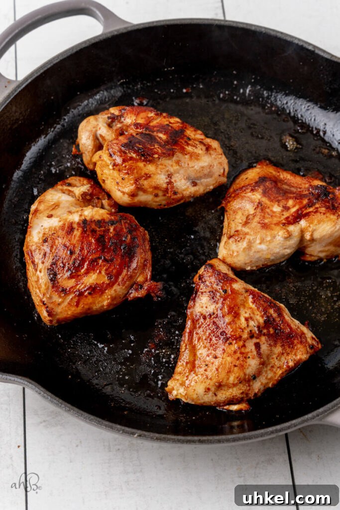 The cooked chicken is browned and cooked with oil in the skillet.