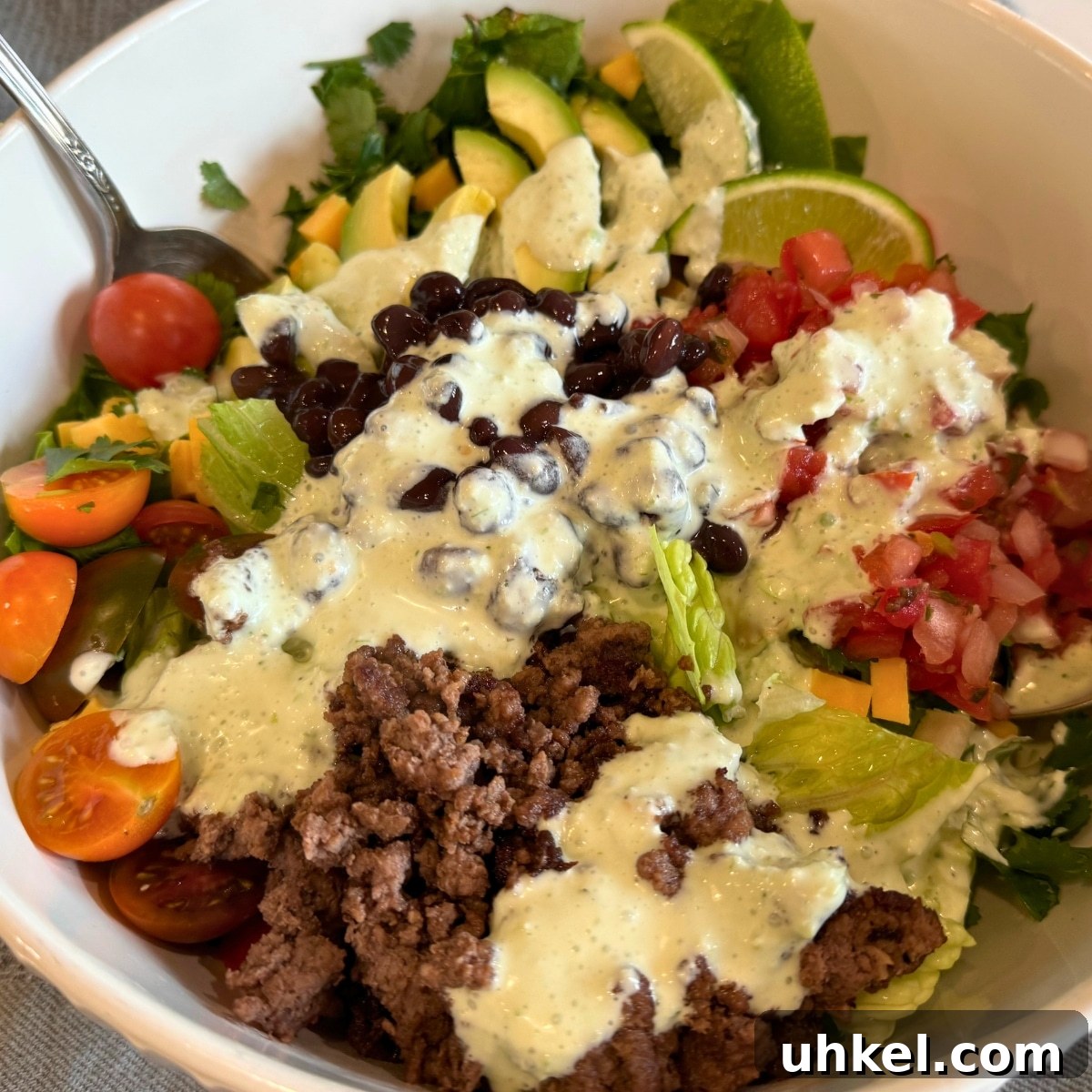 loaded taco salad in a white salad bowl before tossing
