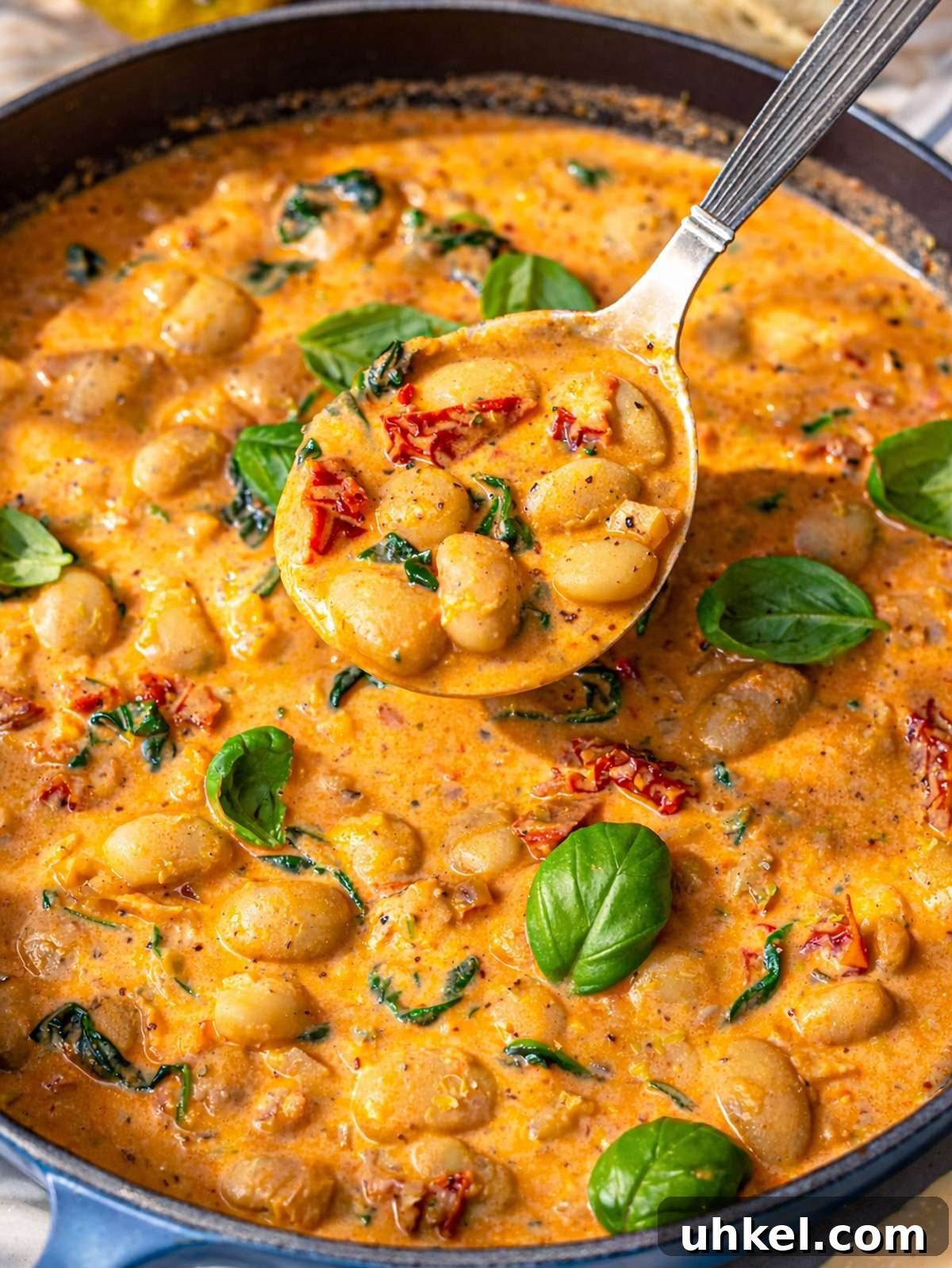 Greek Yogurt Marry Me Butter Beans Recipe 2 Close-up of velvety sun-dried tomato sauce coating large butter beans and wilted spinach.