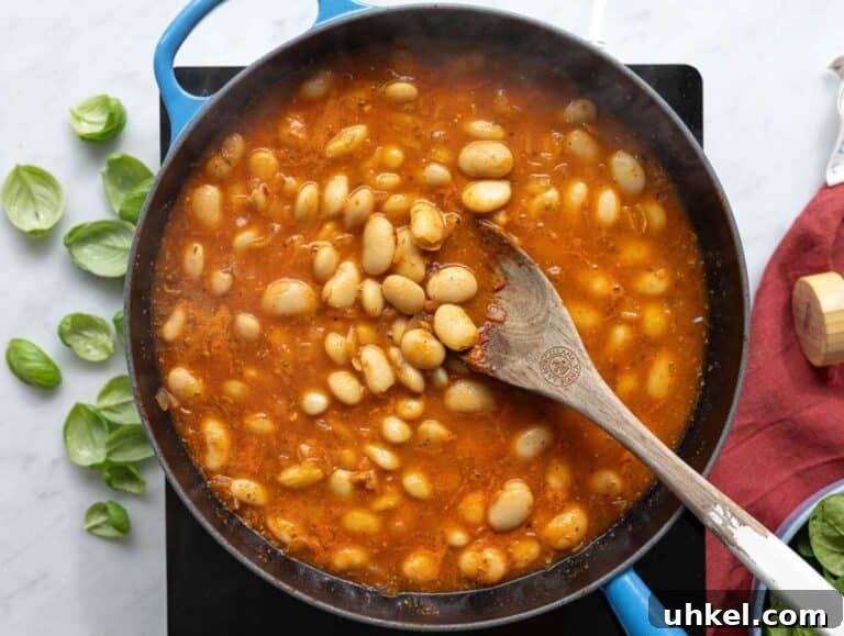 Greek Yogurt Marry Me Butter Beans Recipe 11 Step 2 Plump butter beans being tossed in a rich tomato and garlic base in a pan.