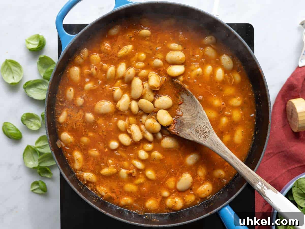 Greek Yogurt Marry Me Butter Beans Recipe 6 Step 2 Plump butter beans being tossed in a rich tomato and garlic base in a pan.