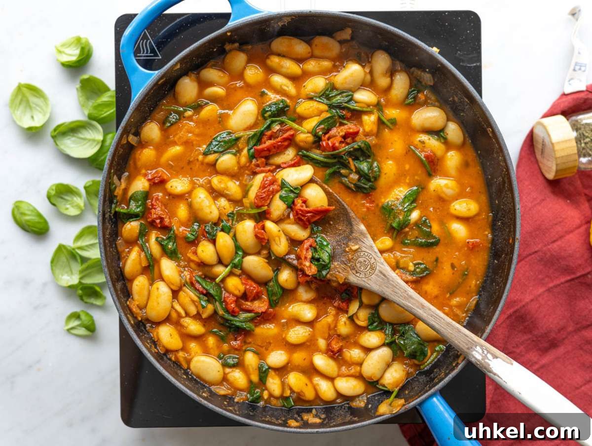 Greek Yogurt Marry Me Butter Beans Recipe 7 Step 3 Butter beans simmering in broth with sun-dried tomatoes and bright green spinach leaves.