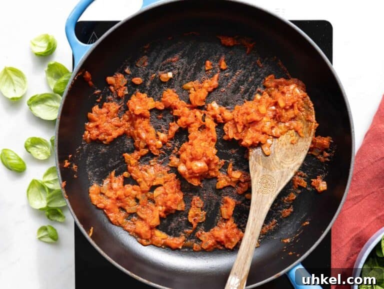 Greek Yogurt Marry Me Butter Beans Recipe 10 Step 1 Sautéing onions, garlic, and tomato paste in a skillet on a marble countertop background.