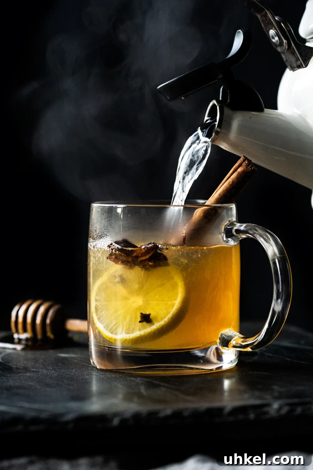 Pouring hot water into a paleo and keto hot toddy with lemon, star anise and a cinnamon stick