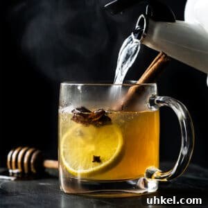 Pouring hot water into a paleo and keto hot toddy with lemon, star anise and a cinnamon stick