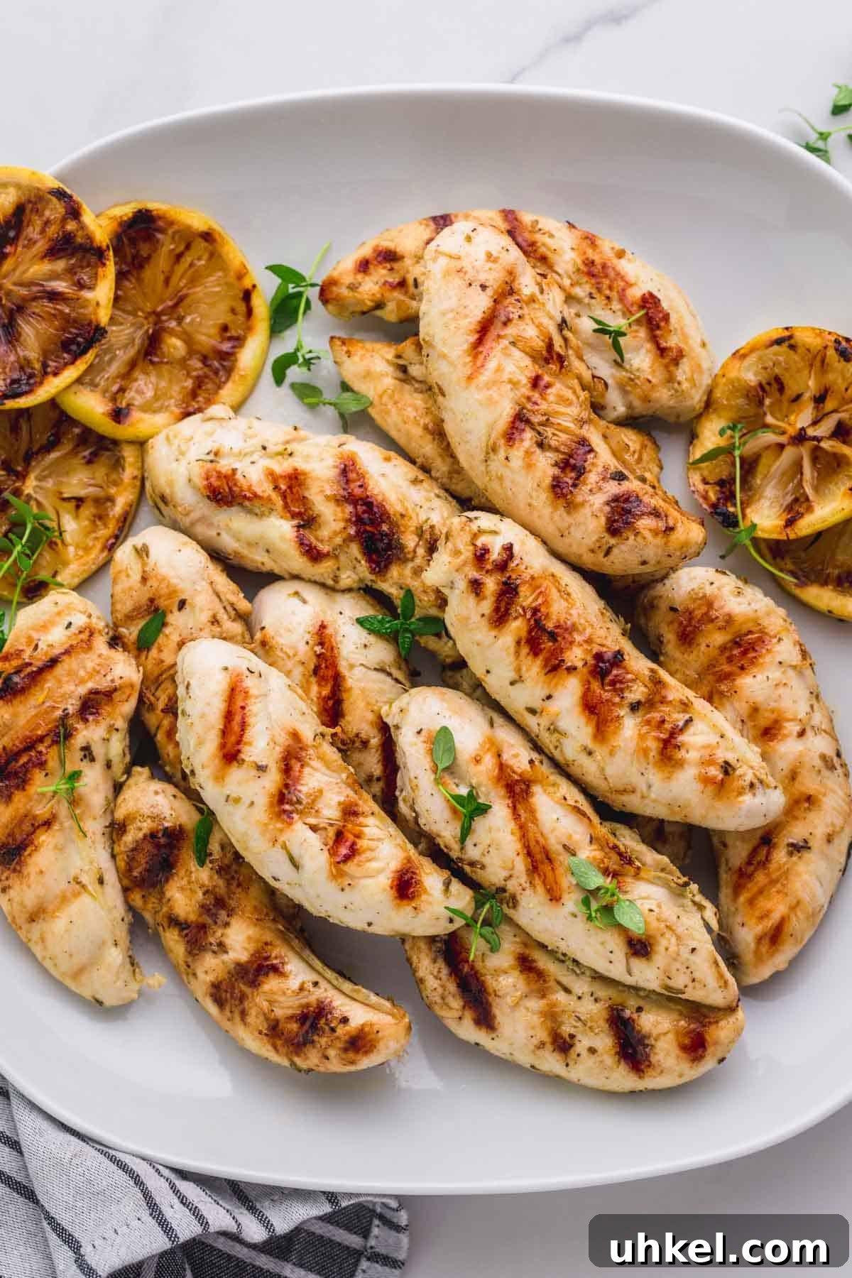 Crispy Grilled Chicken Tenders with Tangy BBQ Glaze 6 Served grilled chicken tenders in a white serving plate, with grilled lemon slices.