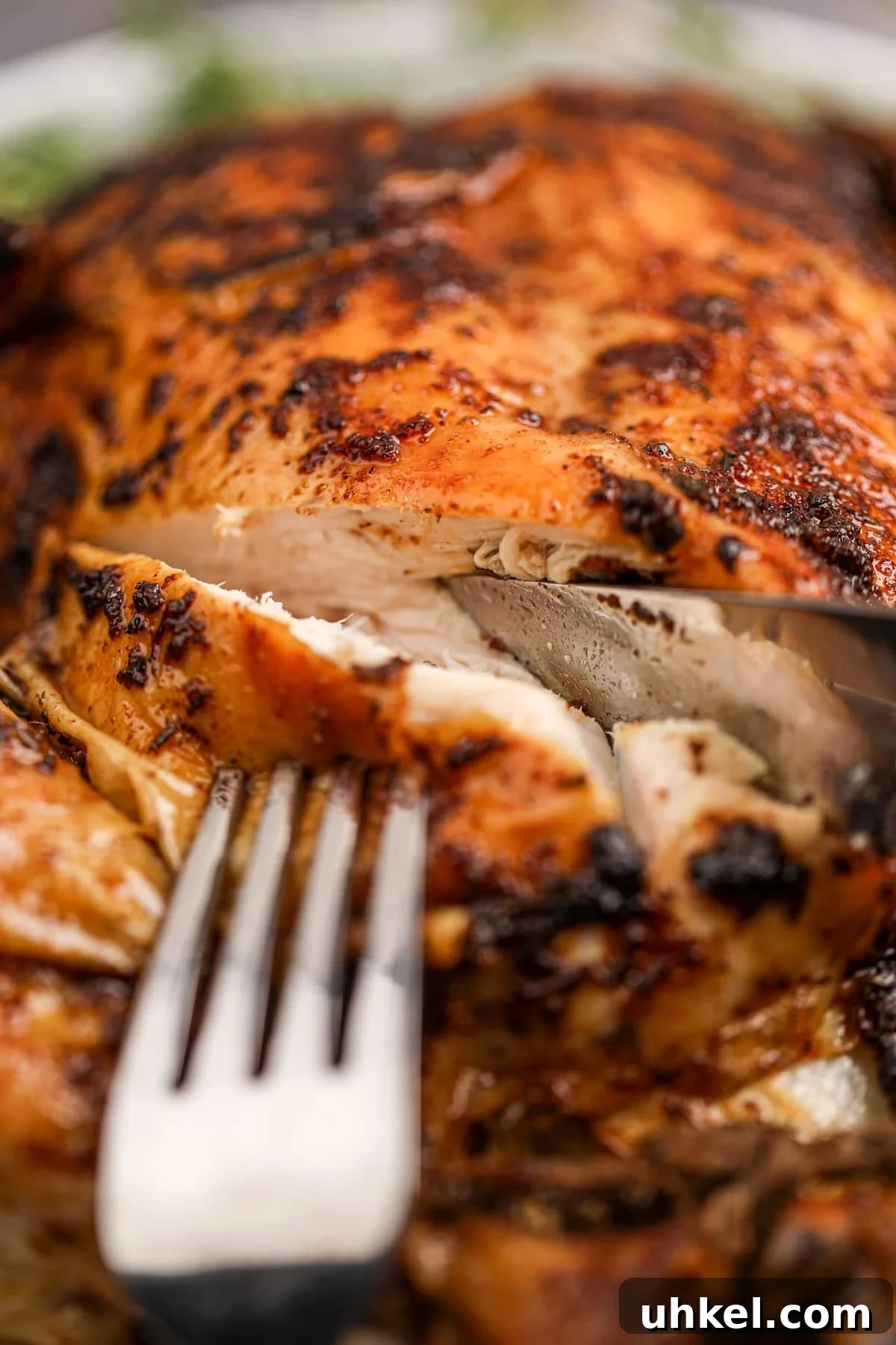 Slicing into a chicken breast, exposing the juicy meat.