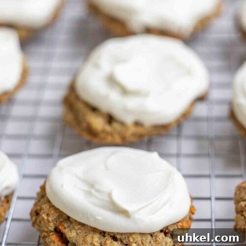 Sourdough carrot cake cookies topped with cream cheese frosting on a wire rack.