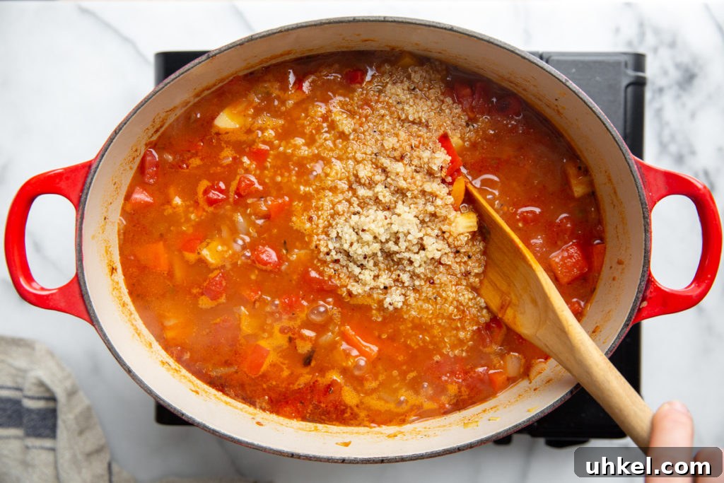 Hearty Vegan Quinoa Chili Recipe: Protein-Packed & Flavorful 10 A hand stirring cooked quinoa into the chili.