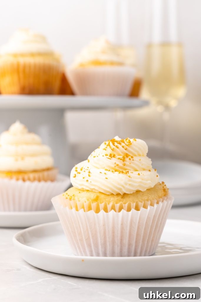 Champagne-Infused Cupcakes: Sparkling Celebration Recipe 12 a gold sprinkle topped champagne cupcake on a small white dessert plate