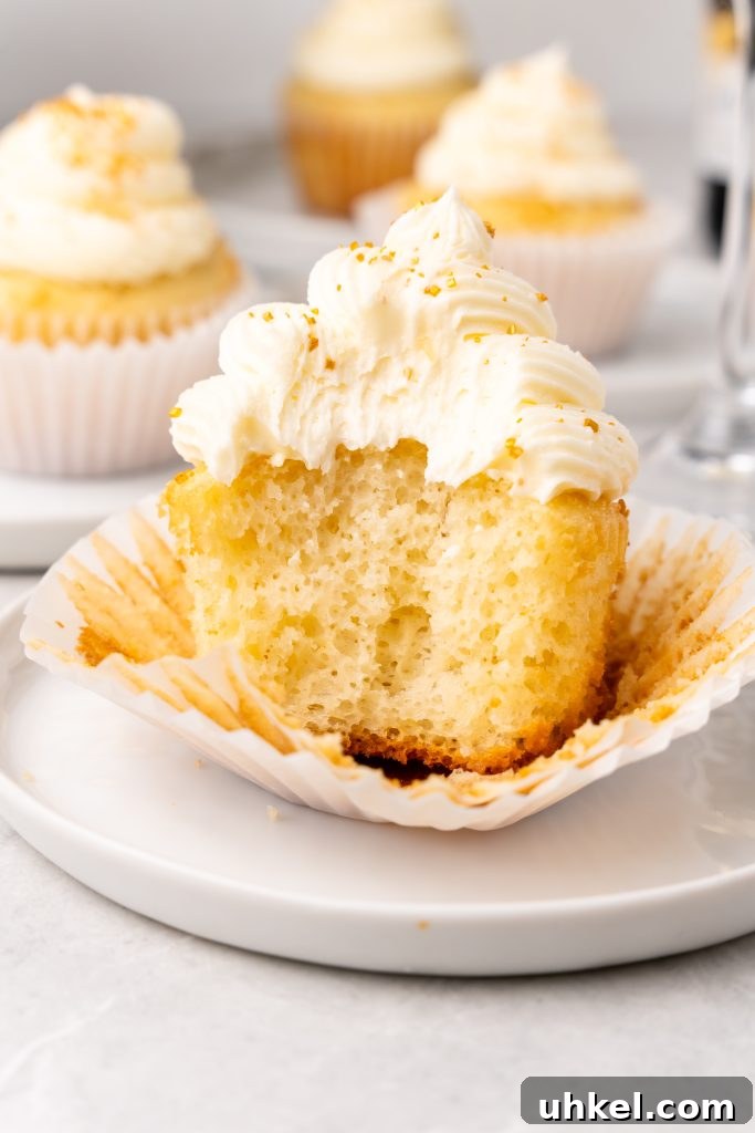 Champagne-Infused Cupcakes: Sparkling Celebration Recipe 13 an unwrapped champagne cupcake with a bite taken out to reveal the fluffy center