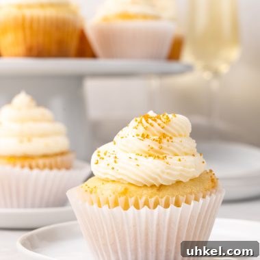 Champagne-Infused Cupcakes: Sparkling Celebration Recipe 14 a gold sprinkle topped champagne cupcake on a small white dessert plate