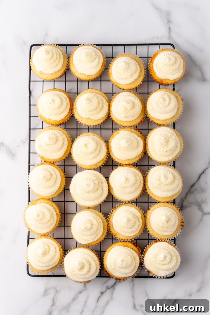 Champagne-Infused Cupcakes: Sparkling Celebration Recipe 9 champagne flavored buttercream frosting on vanilla cupcakes on a metal cooling rack