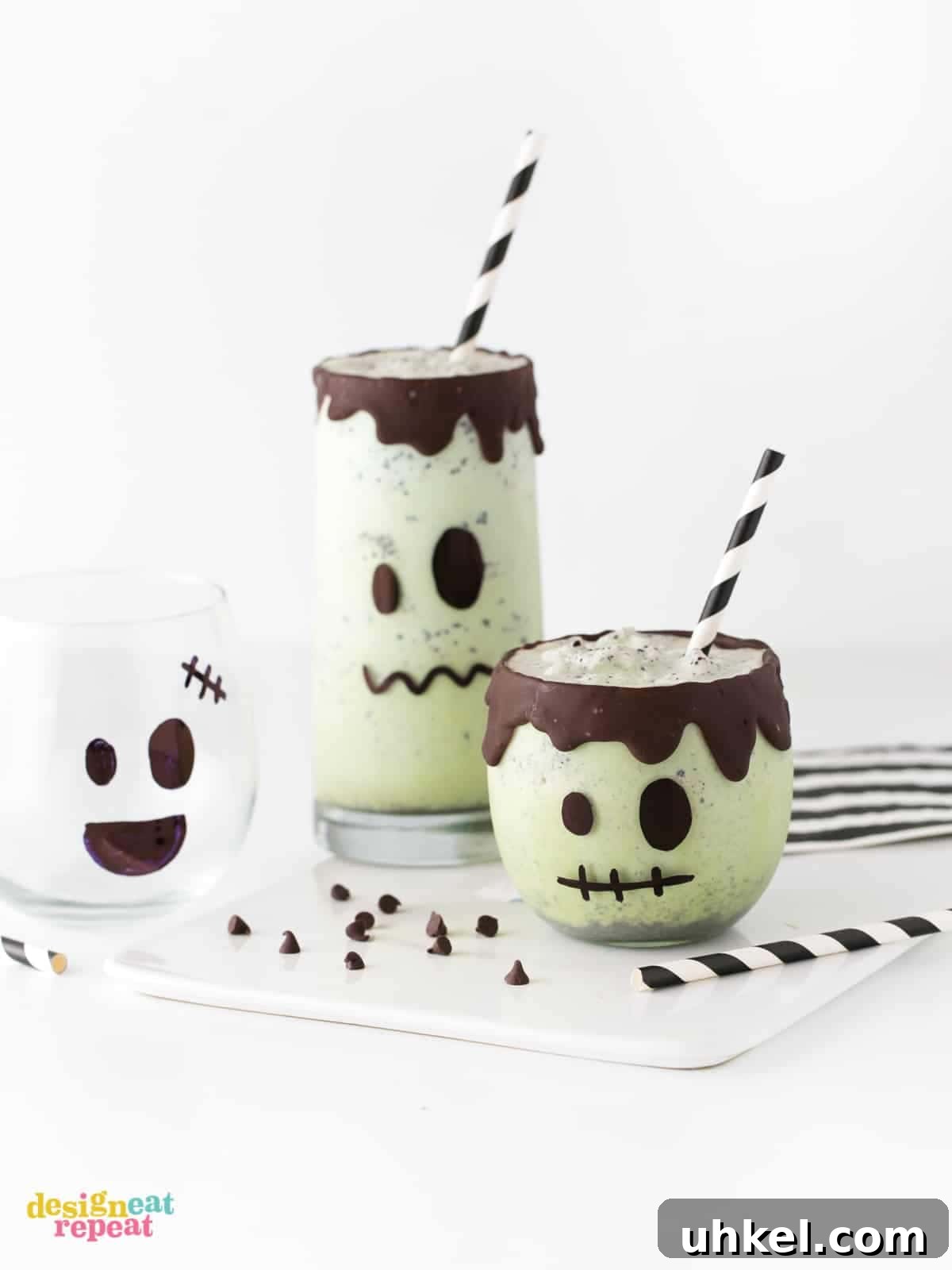 Frankenstein Halloween Milkshakes: Green Monster Dessert Recipe 2 Mint chip green Halloween milkshakes decorated like Frankenstein with chocolate drip rim and striped black paper straws