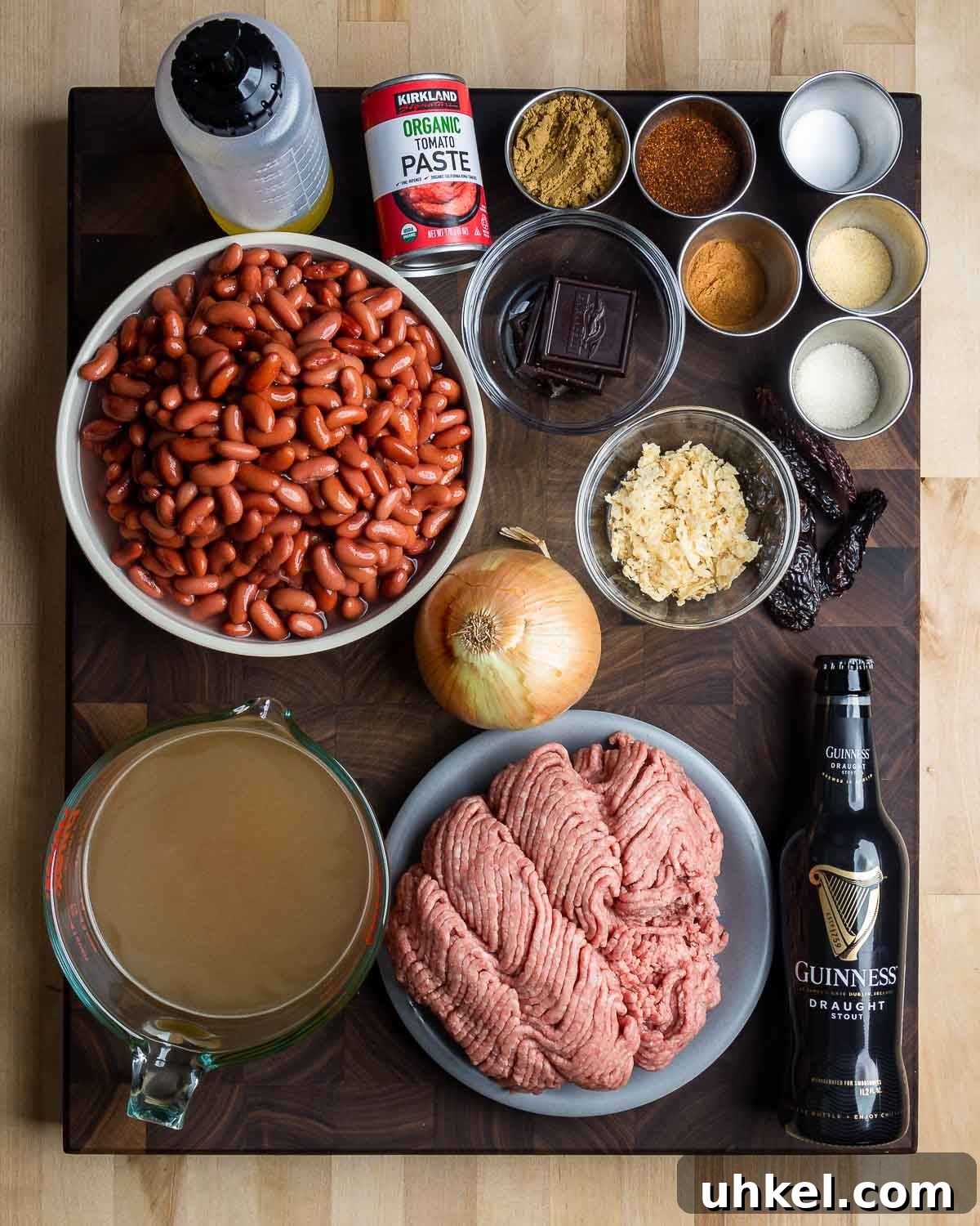 Authentic Classic Chili Recipe for Hearty Weeknight Dinners 3 Ingredients shown: vegetable oil, tomato paste, dark chocolate, chile powder and spices, whole dried chiles, kidney beans, onion, tortilla chips, beef stock, ground chuck, and beer.