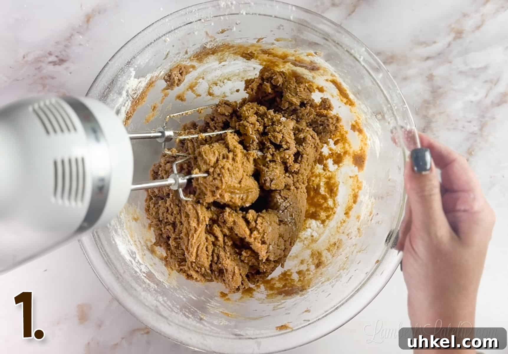 Loaded Cookie Butter Cookies — Gooey Speculoos-Stuffed Treats 4 using a hand mixer to blend cookie dough in a glass bowl.