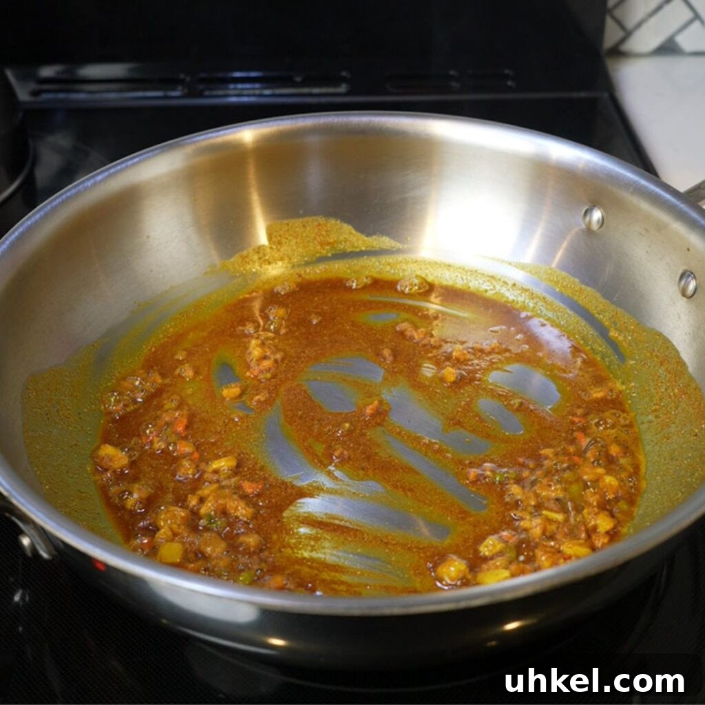 Authentic Jamaican Curry Chicken Recipe: Rich Island Flavor 7 Burning off the curry in oil in a pan.
