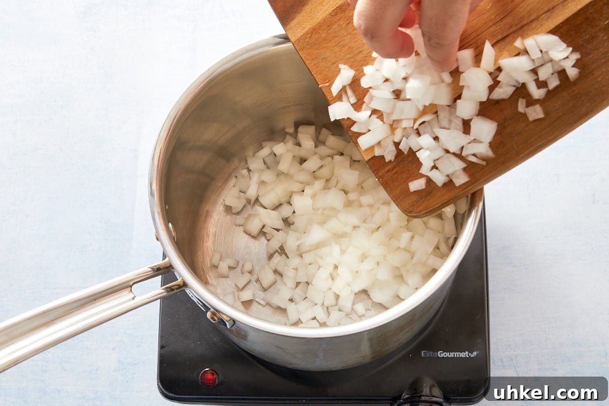 Adding chopped onion to a pot with oil to start the spinach and rice filling.