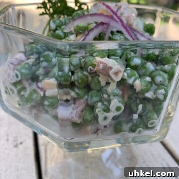 Creamy English Pea Salad with Bacon and Mint 8 Pea salad in a glass serving bowl on an outdoor table.