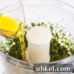 Classic Basil Pesto Recipe: Fresh, Vibrant Sauce for Pasta & More 16 pouring olive oil into the food processor
