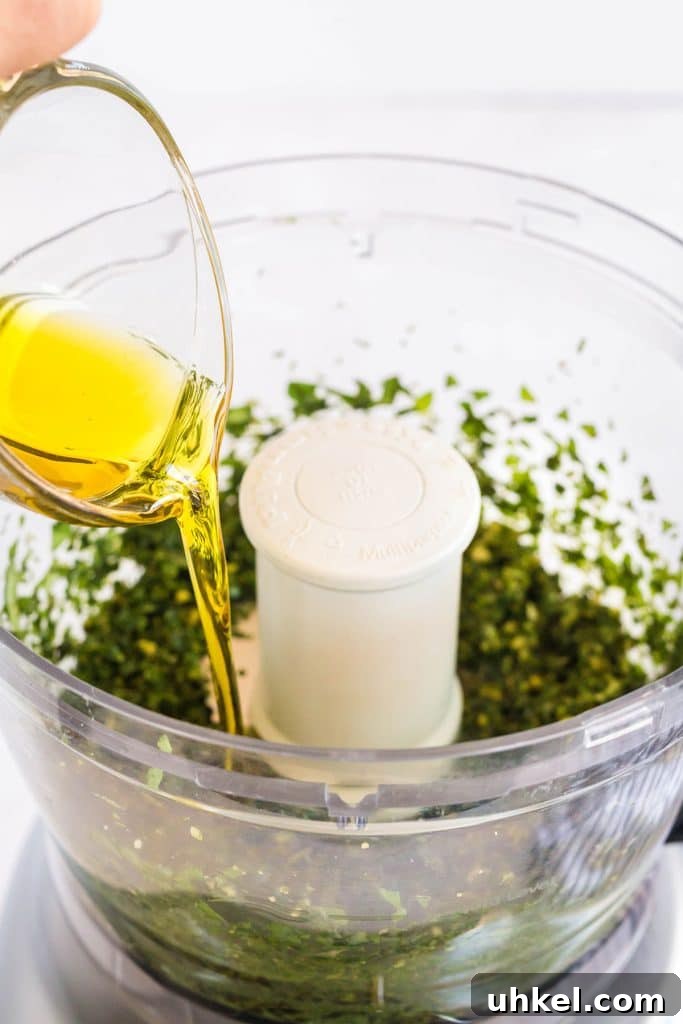 Classic Basil Pesto Recipe: Fresh, Vibrant Sauce for Pasta & More 8 pouring olive oil into the food processor