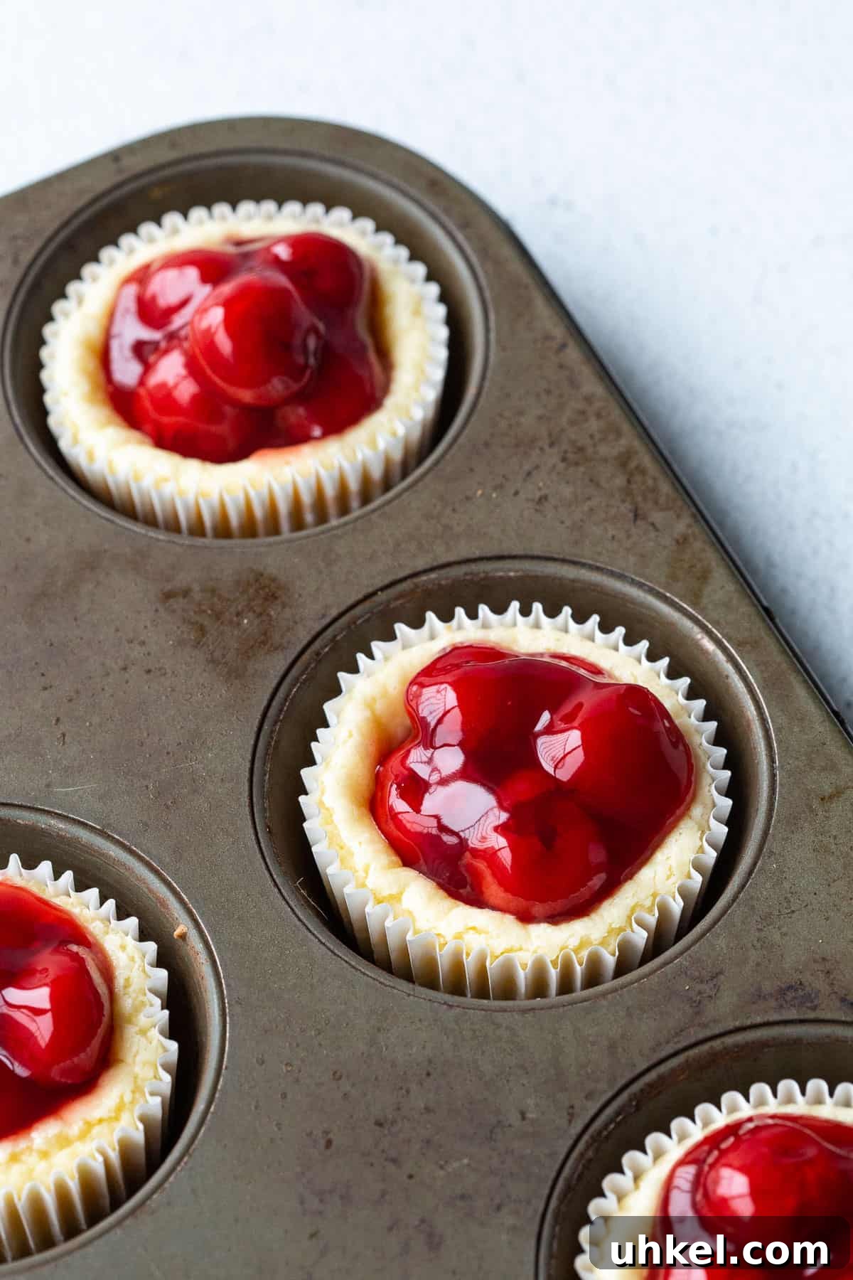 Mini Cherry Cheesecake Bites: Perfect Party Dessert Recipe 7 mini cherry cheesecakes in a muffin tin.