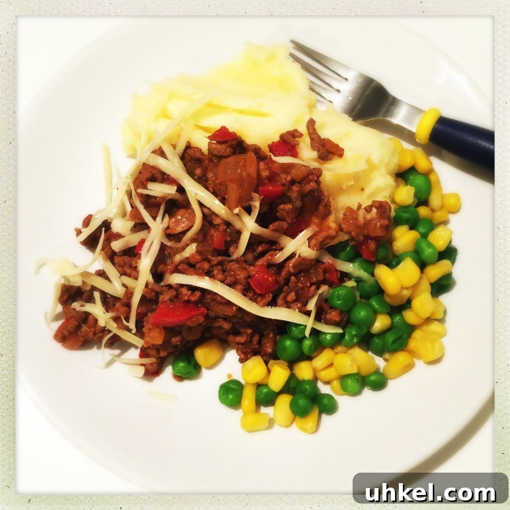 30-Minute Family Dinner Recipes Your Whole Family Will Love 11 white plate with pile of homemade savoury mince served over cheesy mashed potatoes with a side of peas and corn
