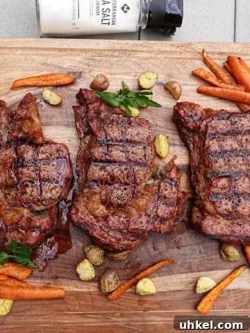 Three smoked steaks on cutting board with carrots and potatoes