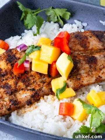 Mahi Mahi fish atop rice and topped with mango salsa in a blue bowl.