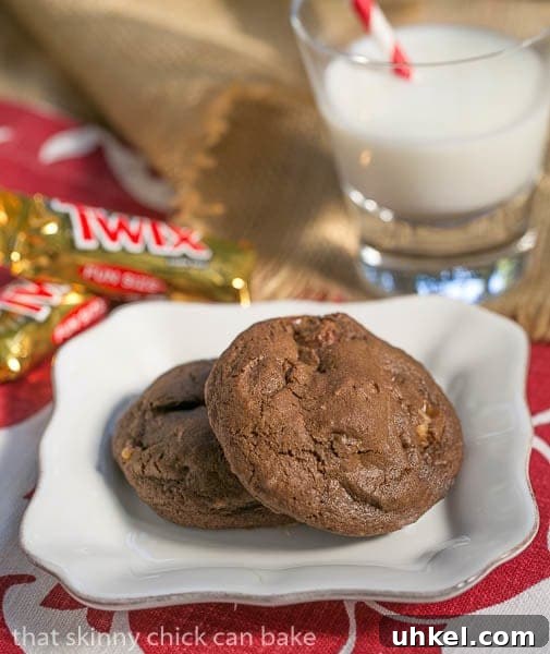 Double Chocolate Twix Cookies - rich, chocolate cookies filled with chunks of decadent Twix bars! Two Double Chocolate Twix Cookies - on a white plate with a glass of milk