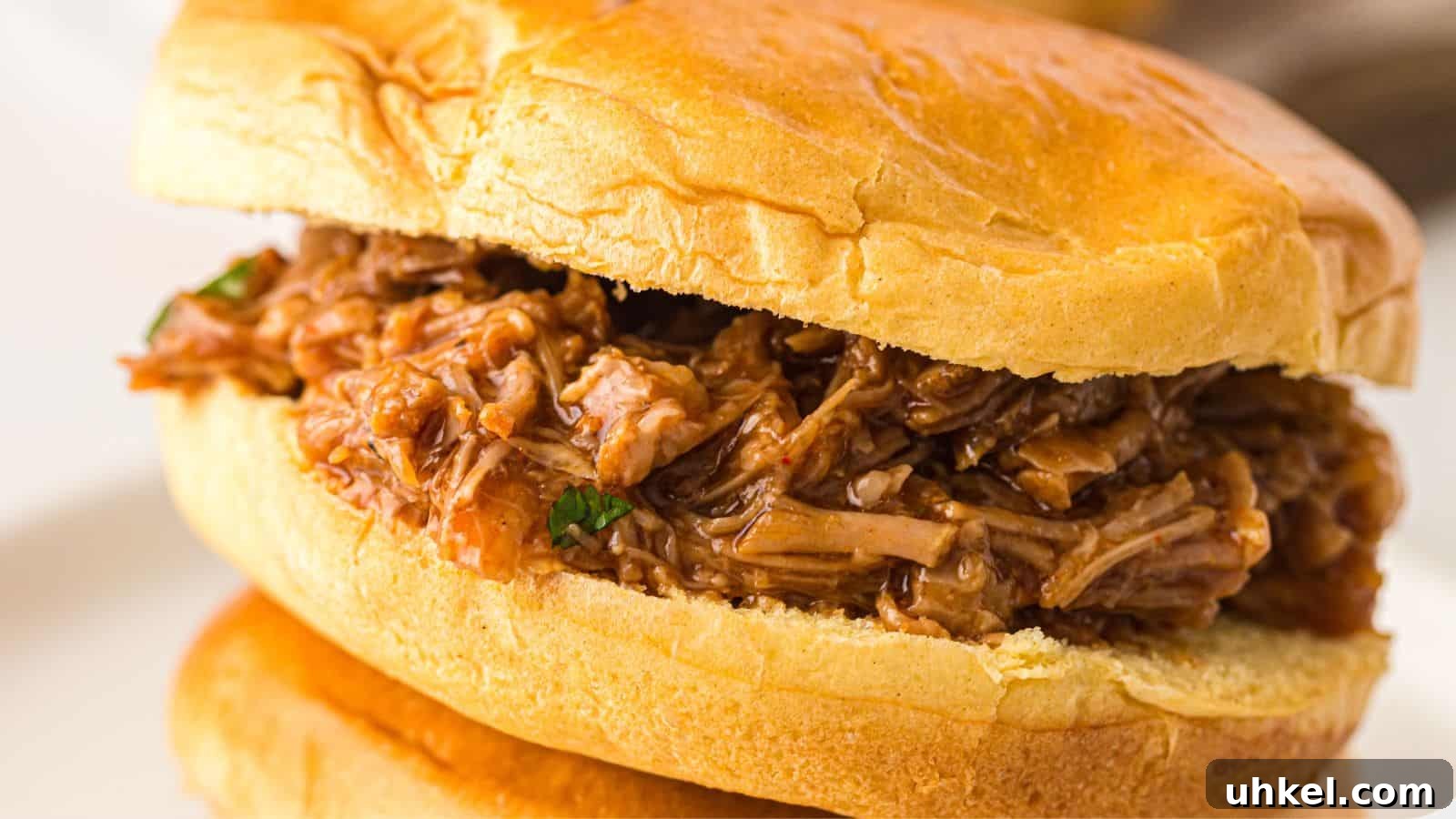 23 Spring Dinner Recipes to Lighten Up Heavy Weeknight Meals 11 A close-up of a pulled pork sandwich on a soft bun, filled with shredded, saucy pork.