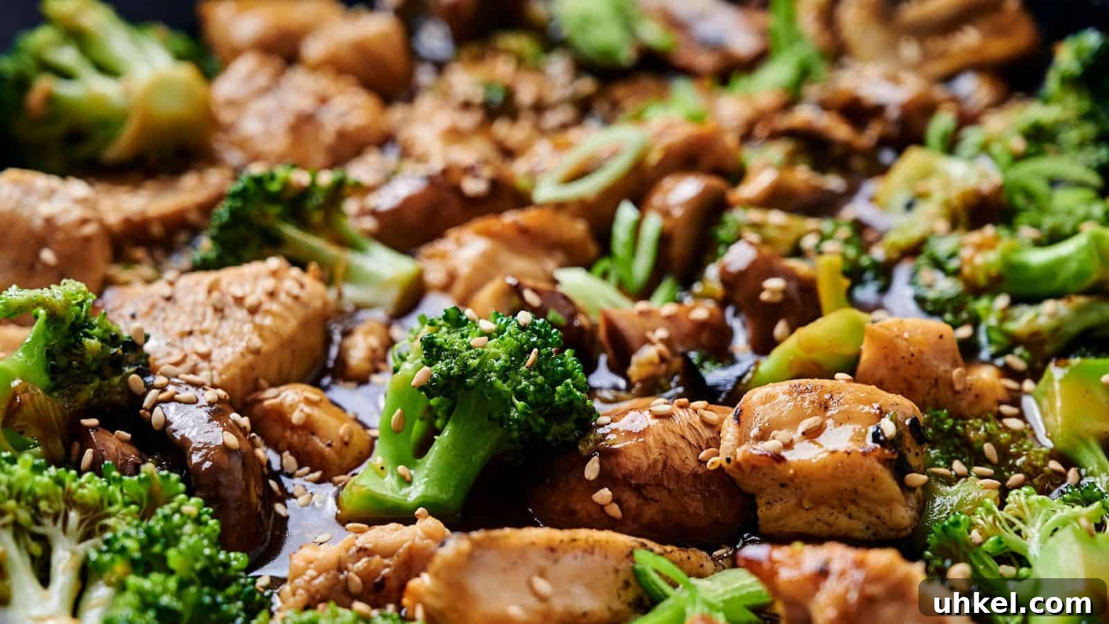 23 Spring Dinner Recipes to Lighten Up Heavy Weeknight Meals 12 Close-up of a stir-fry dish with chicken, broccoli, mushrooms, and sesame seeds, coated in a soy-based sauce.