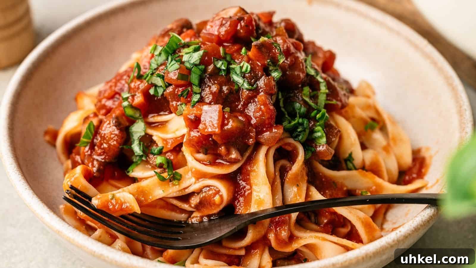 23 Spring Dinner Recipes to Lighten Up Heavy Weeknight Meals 21 A plate of tagliatelle pasta topped with tomato sauce and chopped herbs, with a black fork resting on the side.
