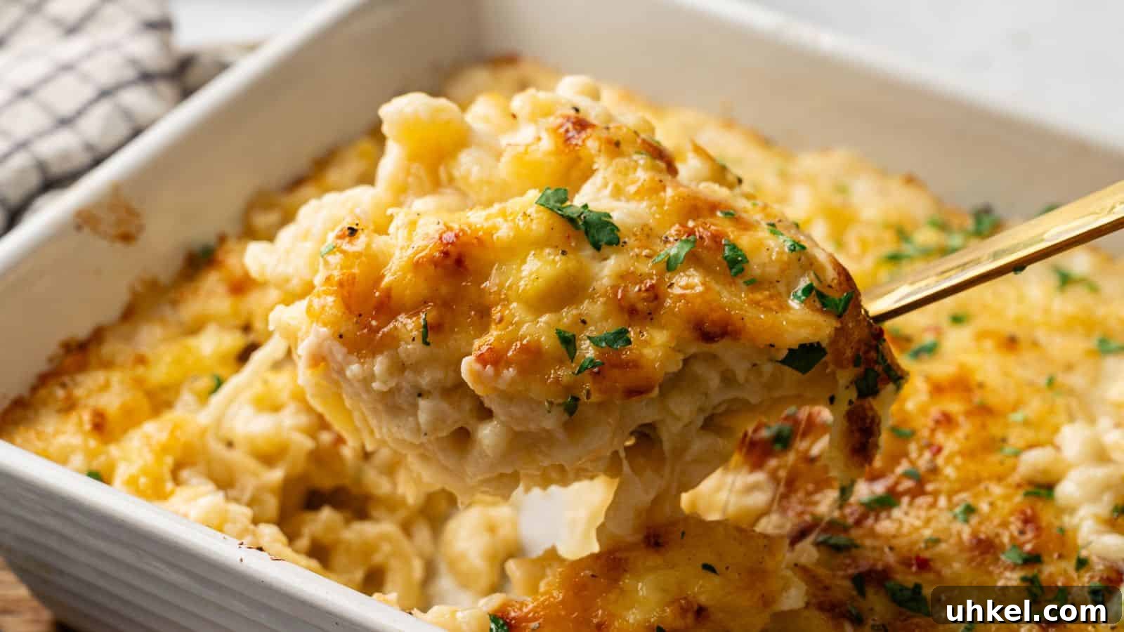 23 Spring Dinner Recipes to Lighten Up Heavy Weeknight Meals 9 A close-up of a serving of baked macaroni and cheese being lifted from a casserole dish, topped with melted cheese and garnished with chopped herbs.