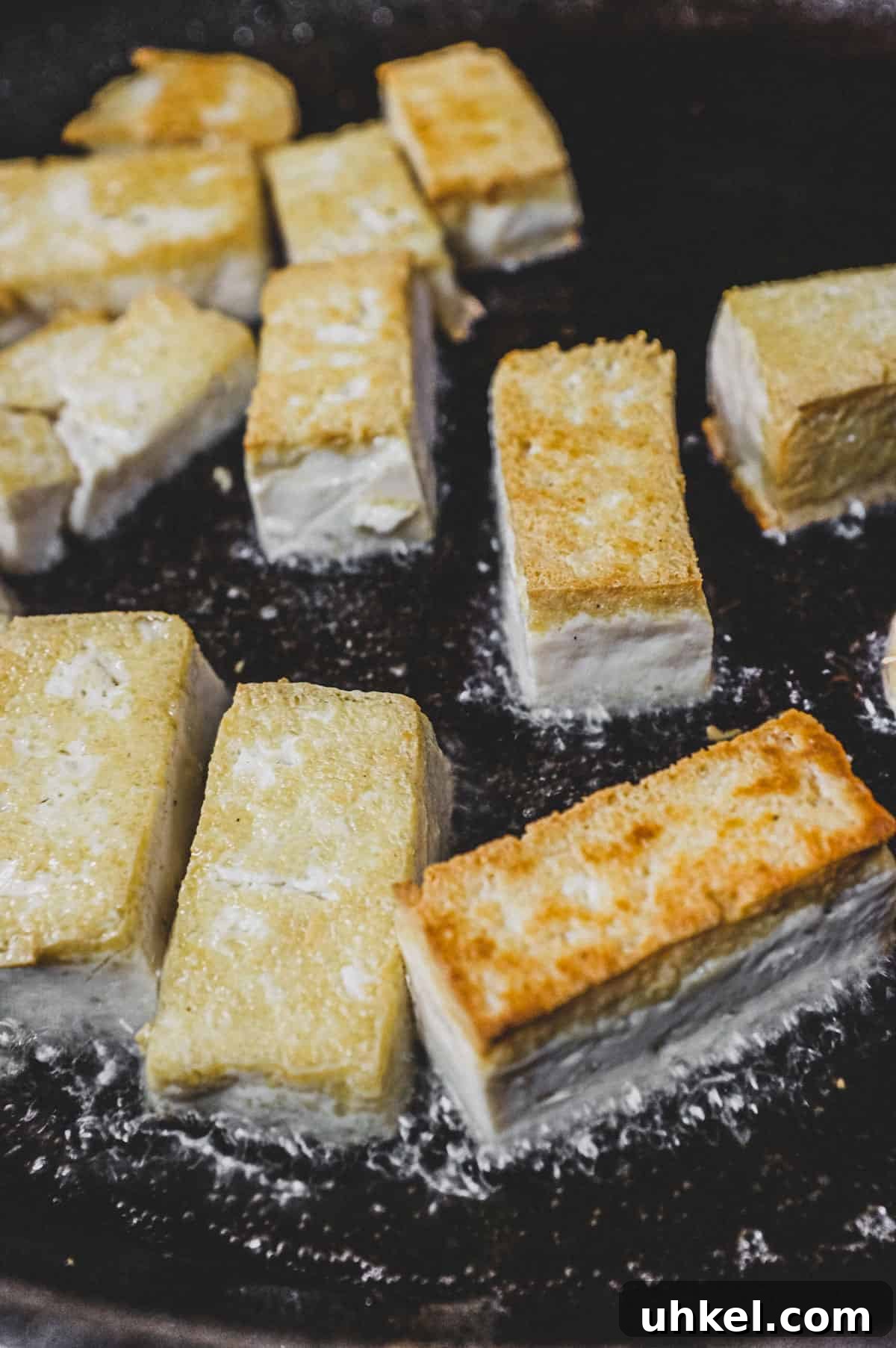 Tofu being fried in canola oil until crisp
